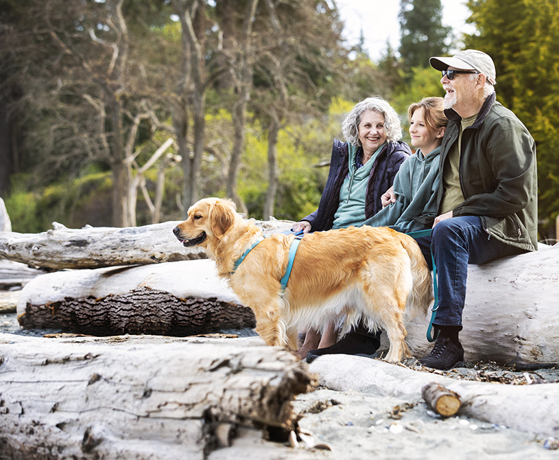 family and dog sitting on a log during a hike