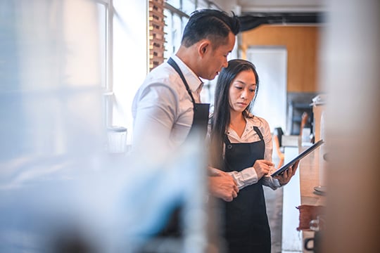 Cafe owners discussing over digital tablet in cafe