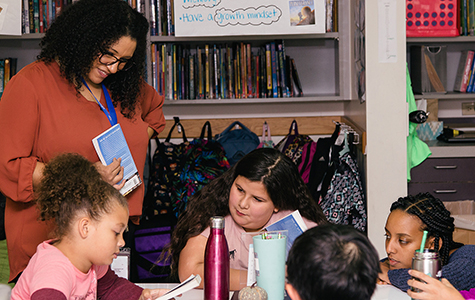 Teacher reviews book with a small group of students in the classroom in Gilbert Heights Elementary