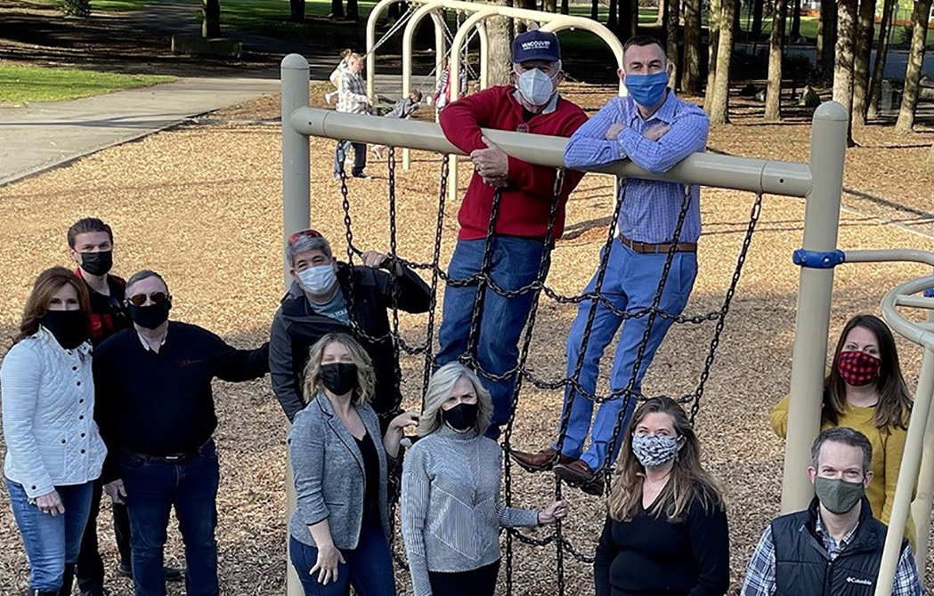 The Parks Board poses on playground equipment.