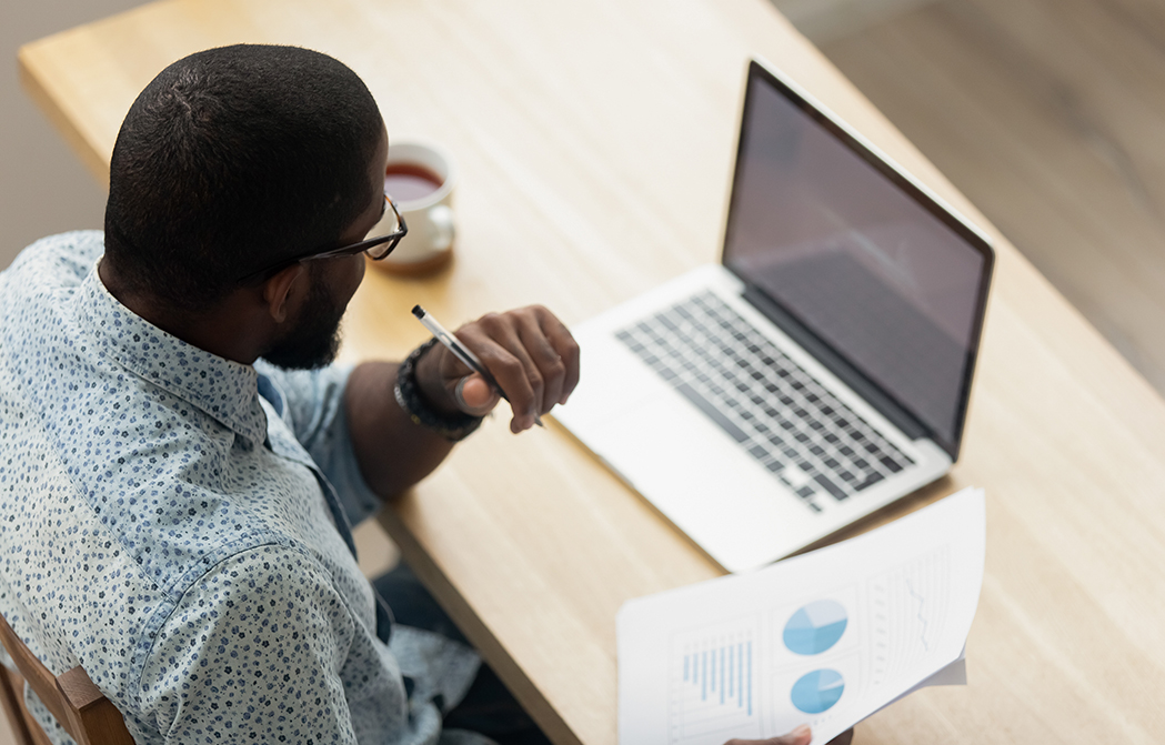 African American man holding charts in front of laptop watching webinar