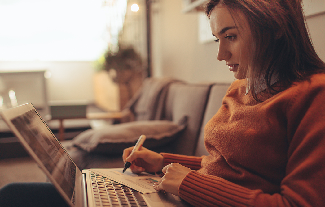 Photo of a young woman sitting at her laptop computer, studying personal finances online