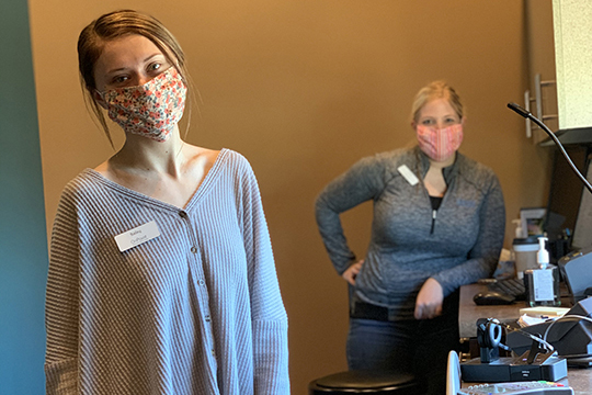 Two OnPoint employees working at a drive-thru winow, with masks