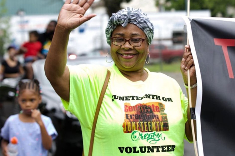 volunteer at Juneteenth parade waving to crowd