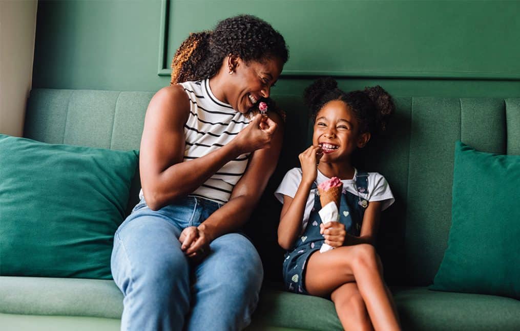 Local leading lender #1 lender portland mother and daughter sitting on green couch eating candy laughing