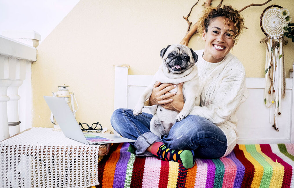 woman at home with pug next to laptop