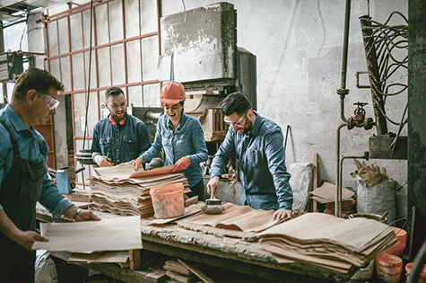 Team Of Carpenters Gluing Wooden Parts Together In Workshop