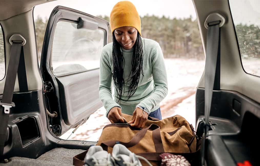girl packing things in car during winter with snow onpoint auto show promo 2025
