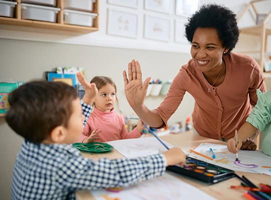 teacher high fiving student while painting community builder 2025
