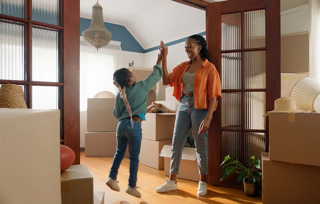 mom and daughter high fiving in new home with moving boxes happy simplifying the home buying process onpoint mortgage