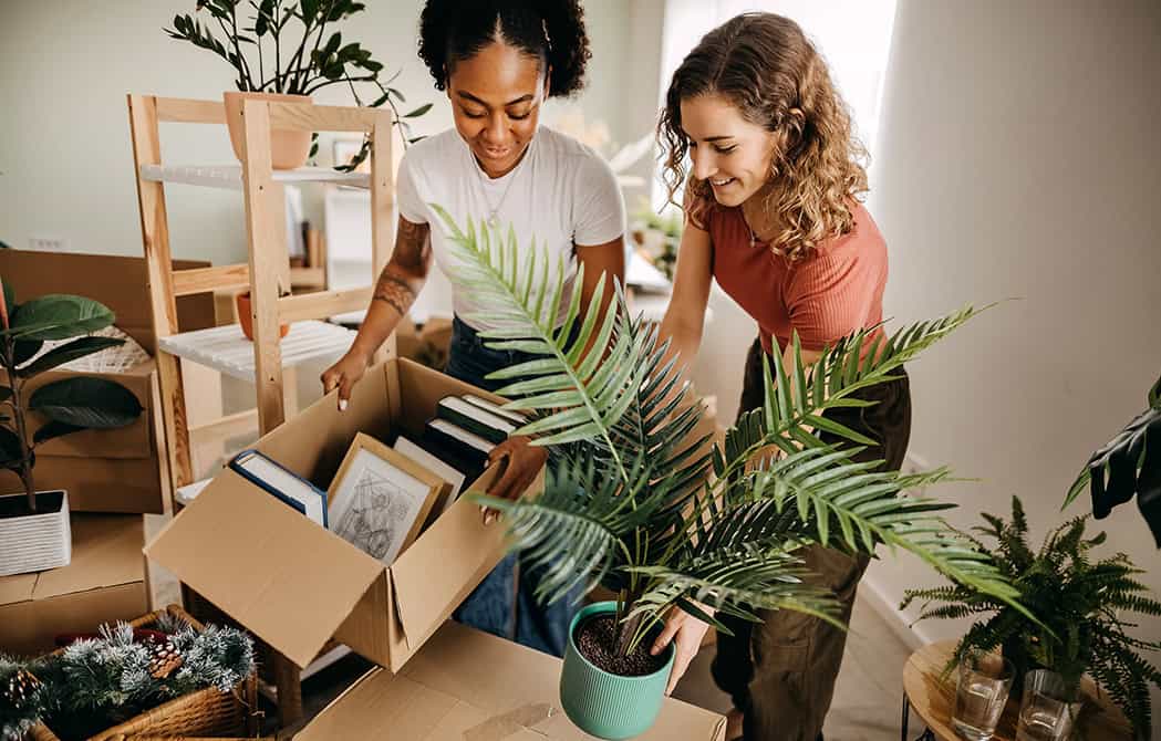 young couple moving boxes and plants in new home together simplifying the homebuying process onpoint trevor reink