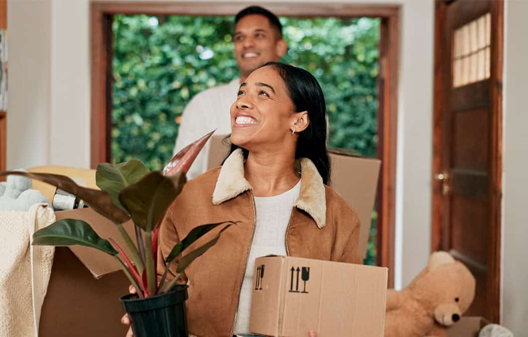 hispanic couple moving in house with boxes and plant happy onpoint mortgage