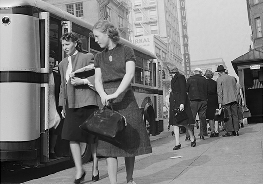 Black and white photo of women exiting public transportation in the 1930s