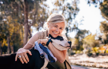 Affectionate mature woman embracing pet dog in nature