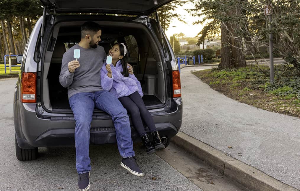 man-sitting-with-daughter-in-the-back-of-a-car-eating-ice-cream