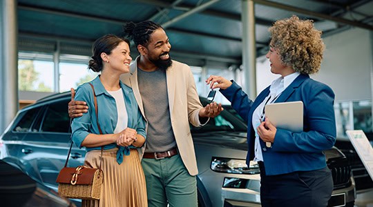 couple purchasing new car from dealership receiving keys