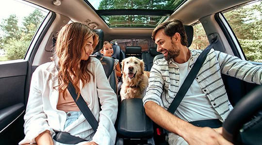 Family in new car with dog and child driving onpoint auto loans