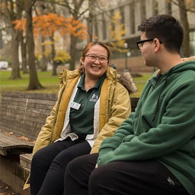 student-being-mentored-outside-sitting-on-bench