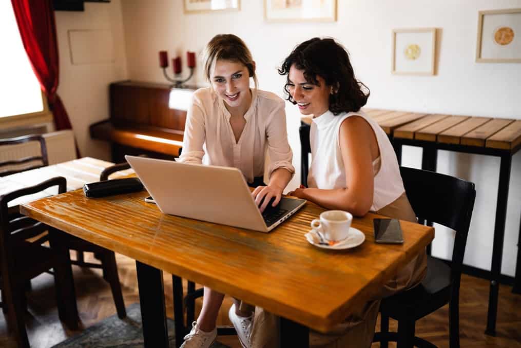 two-women-drinking-coffee-looking-at-computer