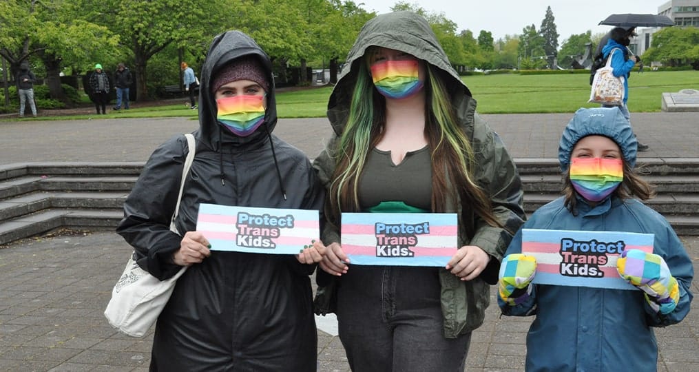 Three people holding signs to advocate for Basic Oregon Rights