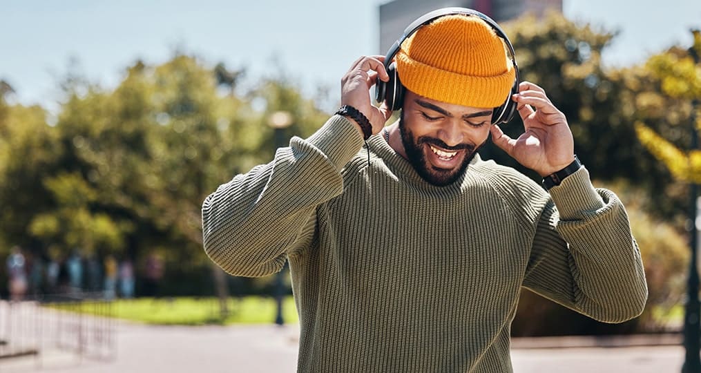 man with headphones wearing an orange beanie