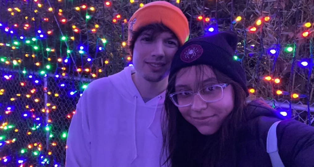 Young couple posing for photo with Christmas lights