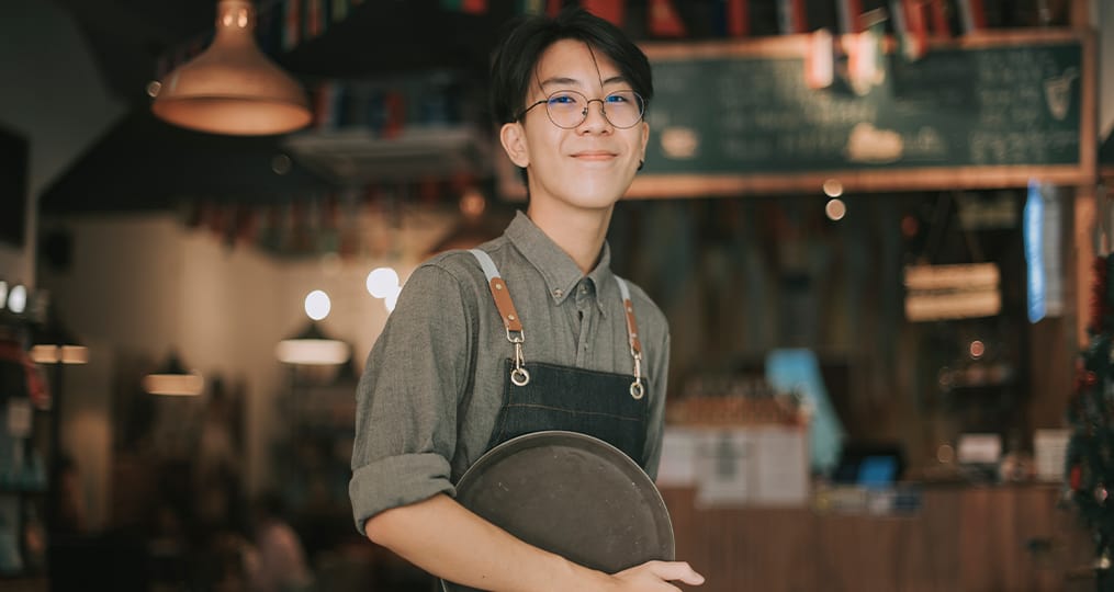 boy-waiter-looking-at-camera-smiling-work-at-cafe-opening