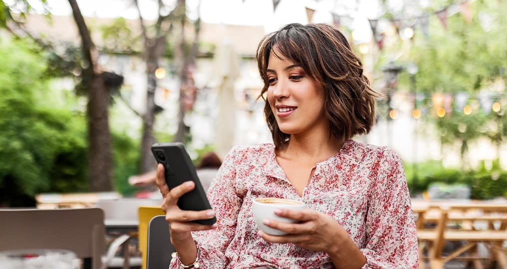 woman-on-her-phone-drinking-coffee-outside