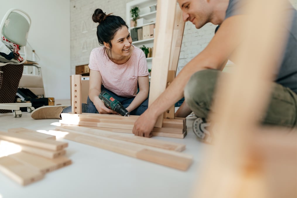 couple sitting down constructing household furniture