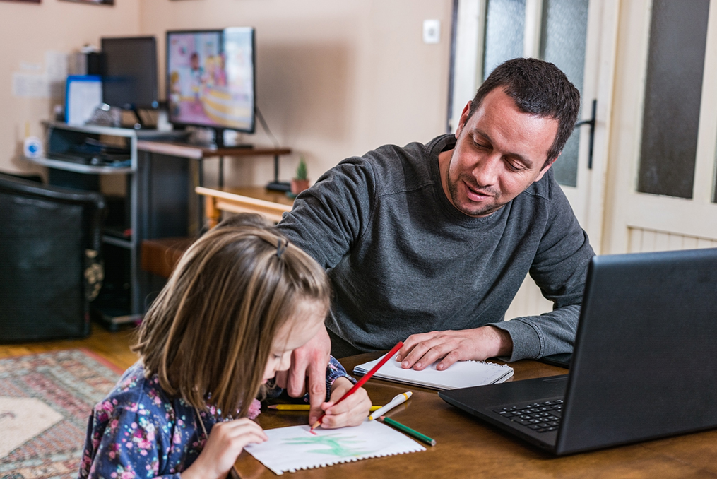 5 Steps to Take If You Lost Your Job in Oregon State_Man slooking for a job from home while helping his daughter with schoolwork