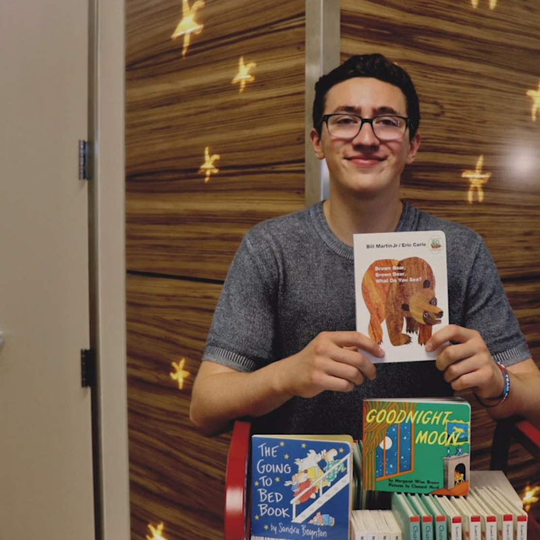 Community Impact Story - Babies With Books_Benjamin holding up a book at the hospital in NICU
