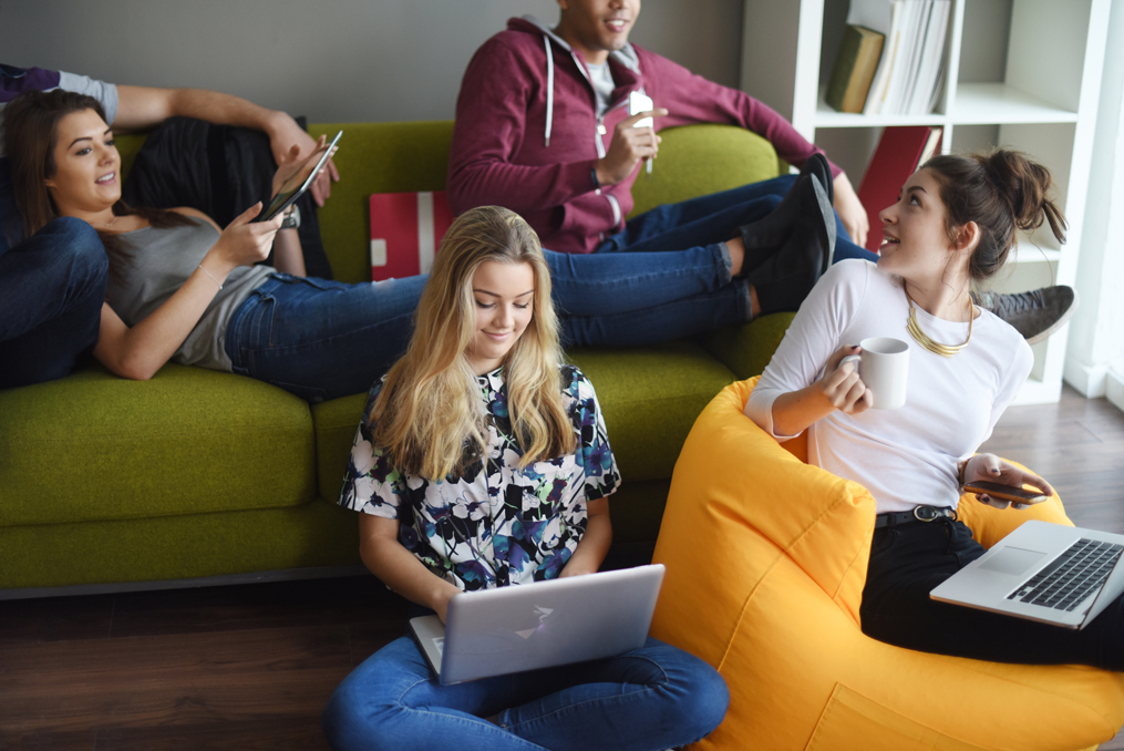 How saving teaches children about financial responsibility_kids sitting around a couch with their electronics reviewing a savings account for kids