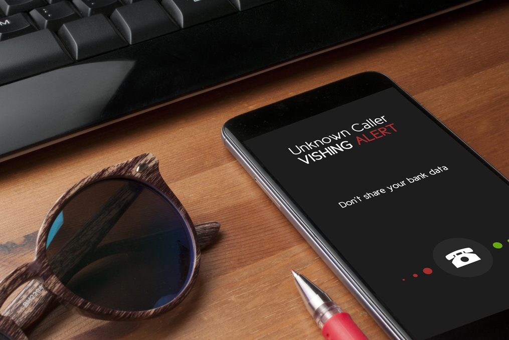 Vishing How to Protect Yourself From Phone Fraud_phone on table near laptop showing incoming call and vishing alert