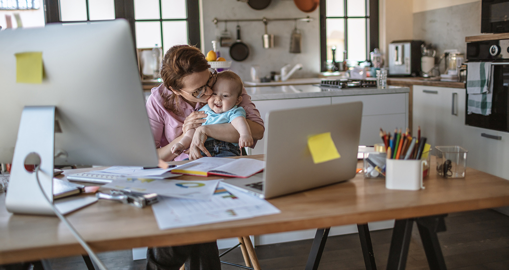 Building a Legacy of Financial Literacy-mom kissing baby while sitting at the dining table doing finances