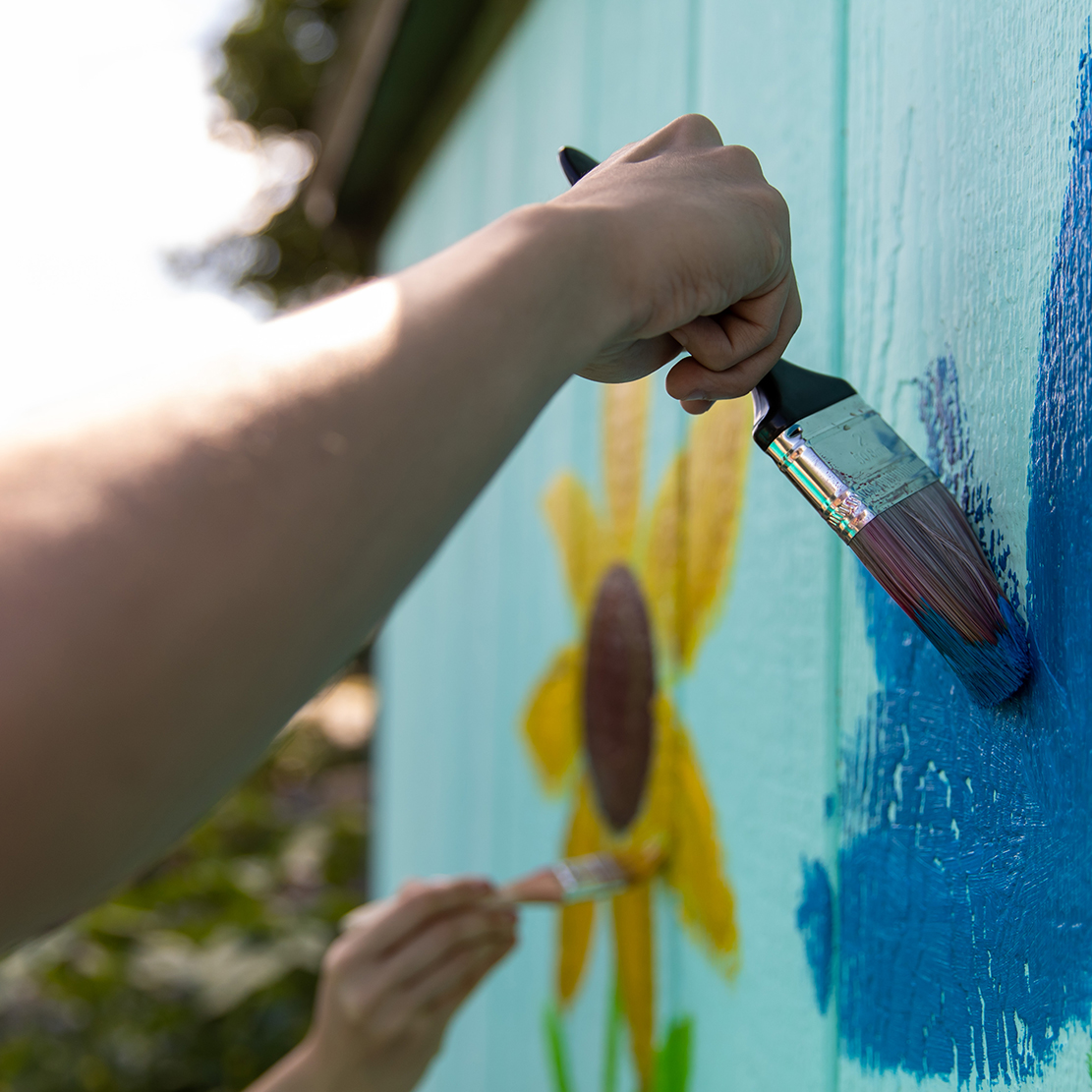 Help Decide the Winner of OnPoint's $5,000 Community Builder Award-hand painting a mural in a garden