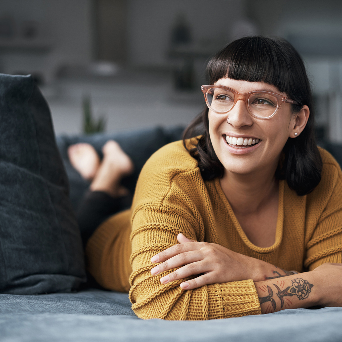 4 smart ways to use your tax refund_woman smiling and thinking on her couch