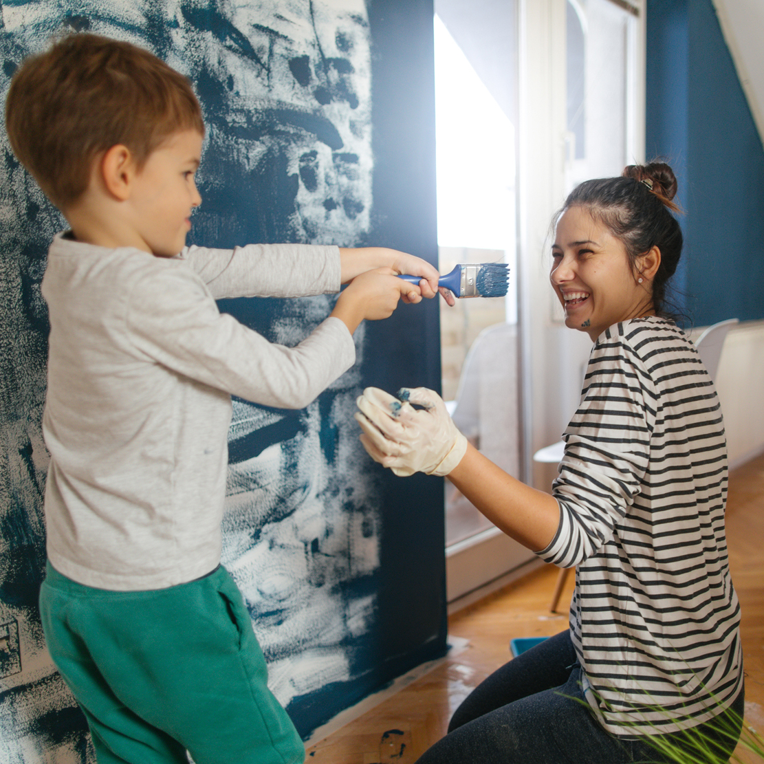 mom and son having fun while painting a bedroom wall