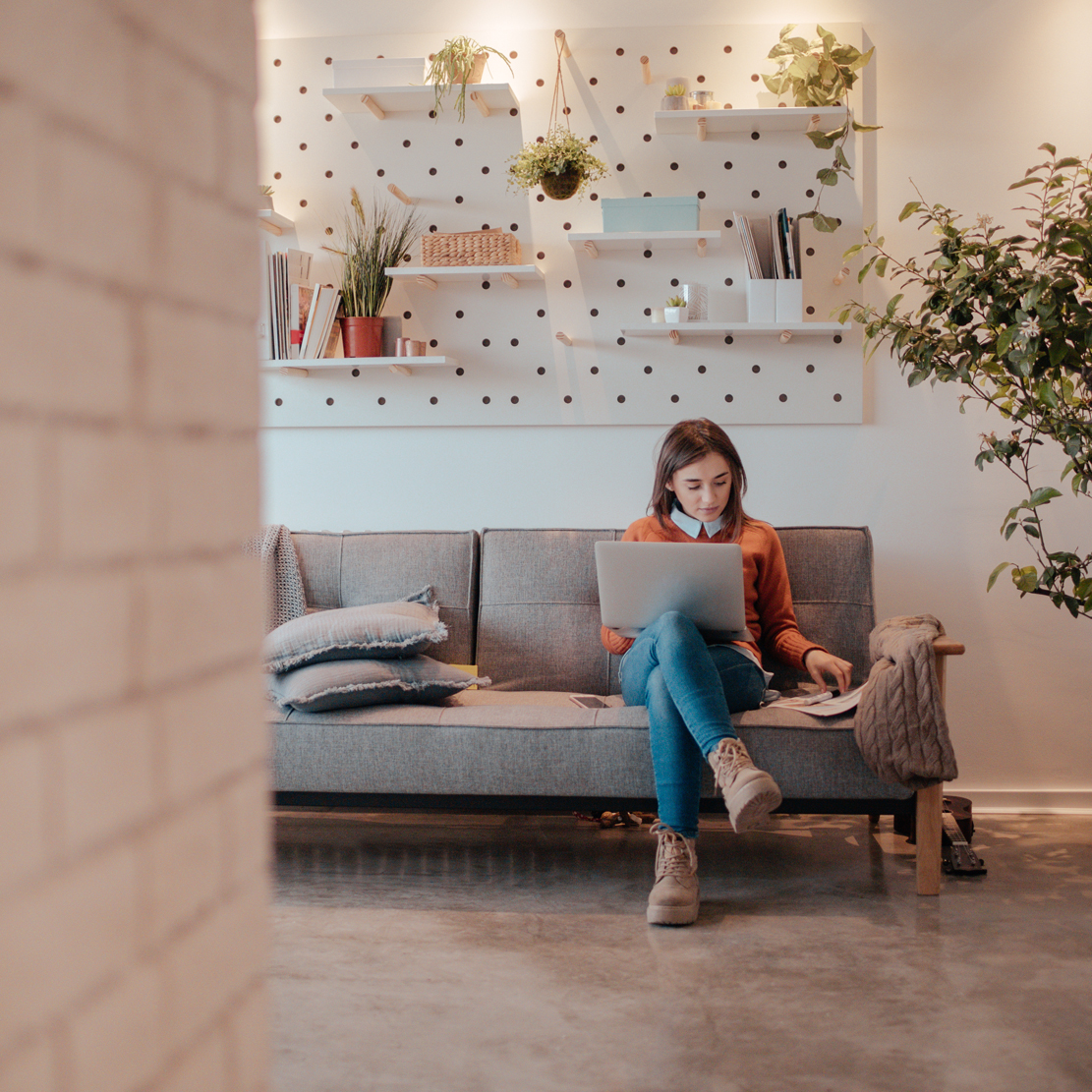 Young woman sitting on her couch with her laptop