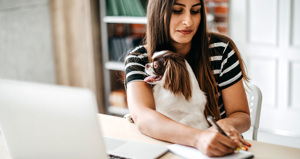 How to Avoid Job Hunt and Apartment Rental Scams_Woman writing notes while holding her dog in her lap