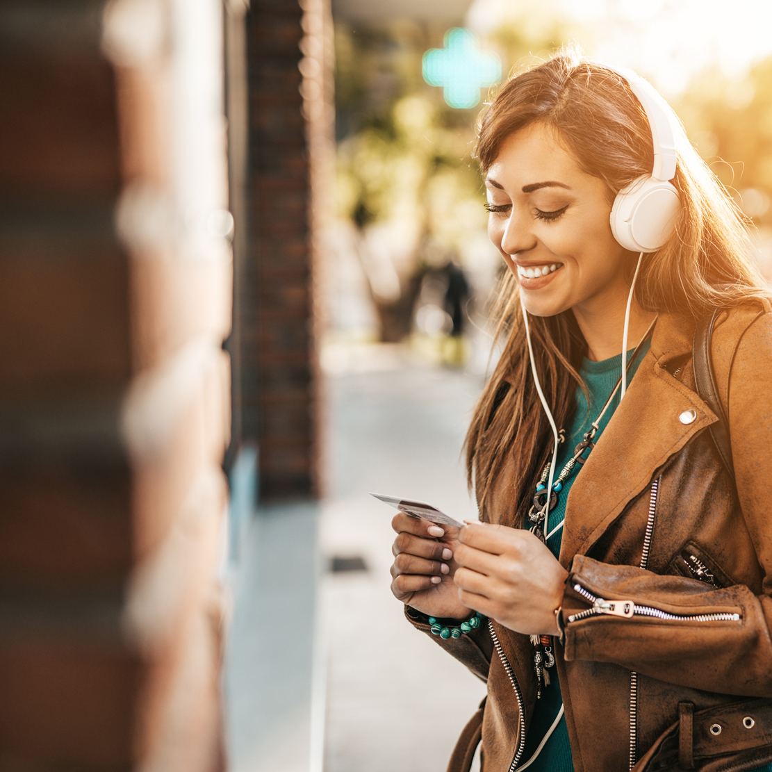 How to avoid ATM fees_holding her debit card and smiling
