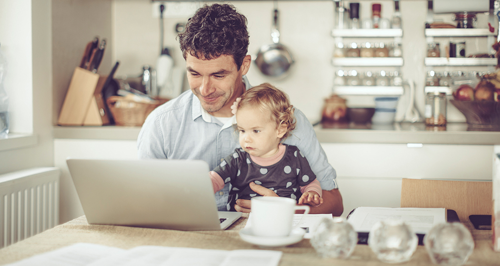 Strategies for Quitting the Paycheck-To-Paycheck Life_Father and child sitting at the kitchen table looking at laptop