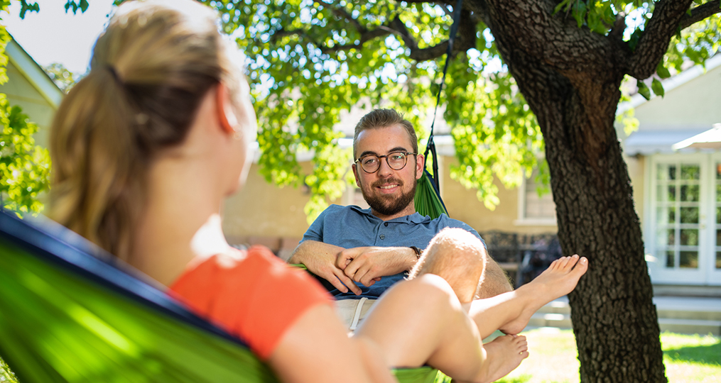 Take the time to organize your finances_Young man and woman sitting in a hammock having a discussion