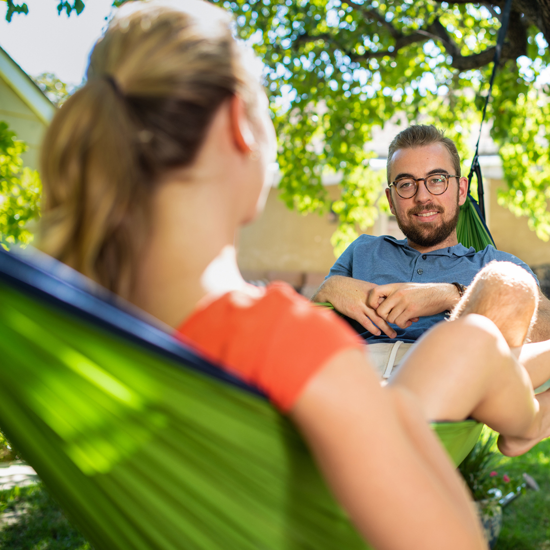 Take the time to organize your finances_Young man and woman sitting in a hammock having a discussion