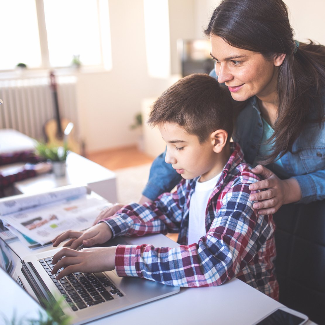 The Biggest Cybersecurity Questions for Parents_Mom encouraging son to use laptop