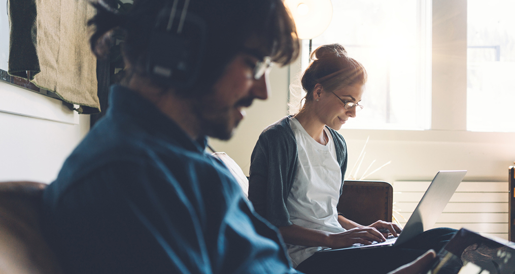 Why You Should Open Multiple Savings Accounts_Exploring savings options - woman at her computer next to man listening to music