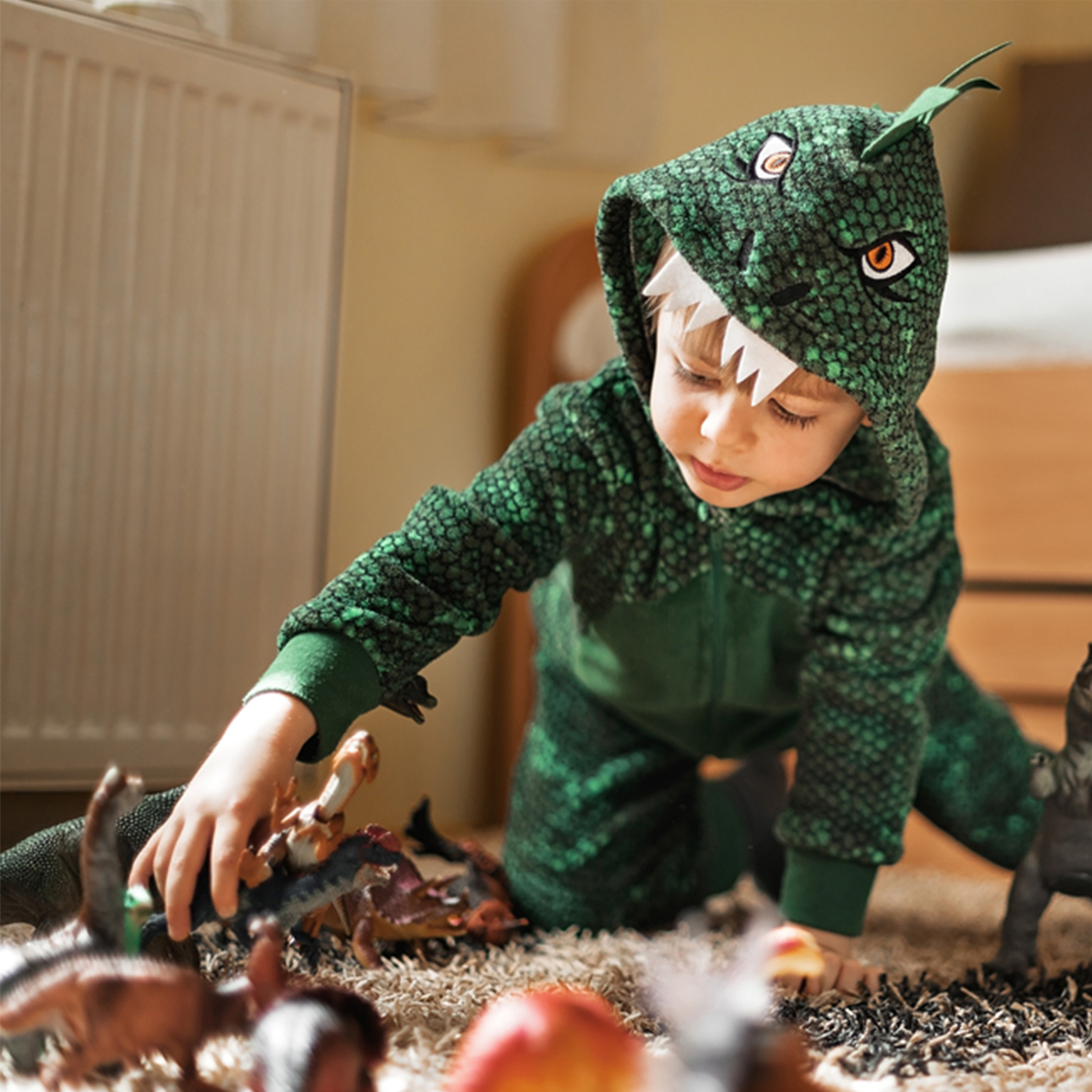 Youth Literacy Month 2021_young boy in dinosaur costume playing with toys in his bedroom