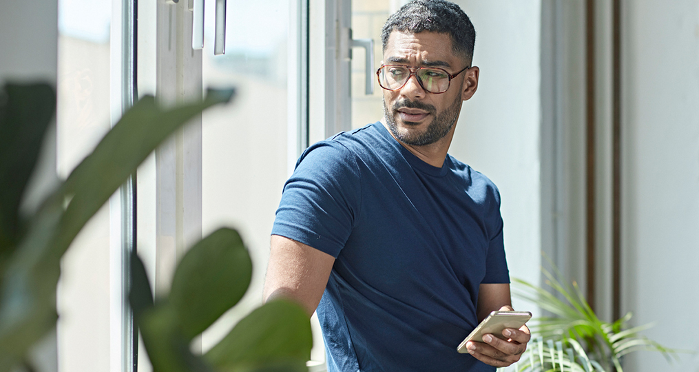 how to prevent peer to peer payment fraud_concerned man looking out the window while he holds his phone