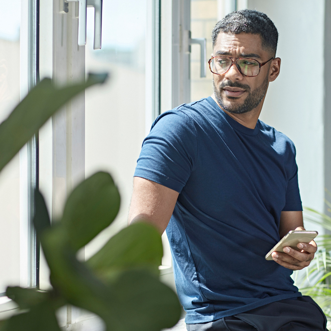 how to prevent peer to peer payment fraud_concerned man looking out the window while he holds his phone