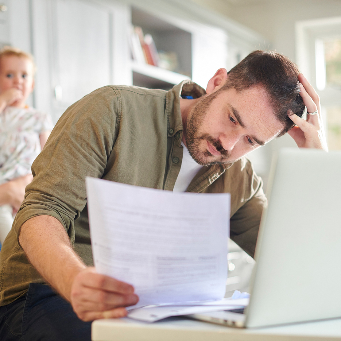 managing personal finances during a crisis_Man sitting at kitchen table reviewing bills