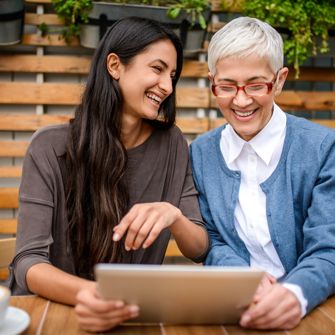 woman and her grandma looking at a tablet together sitting on the patio